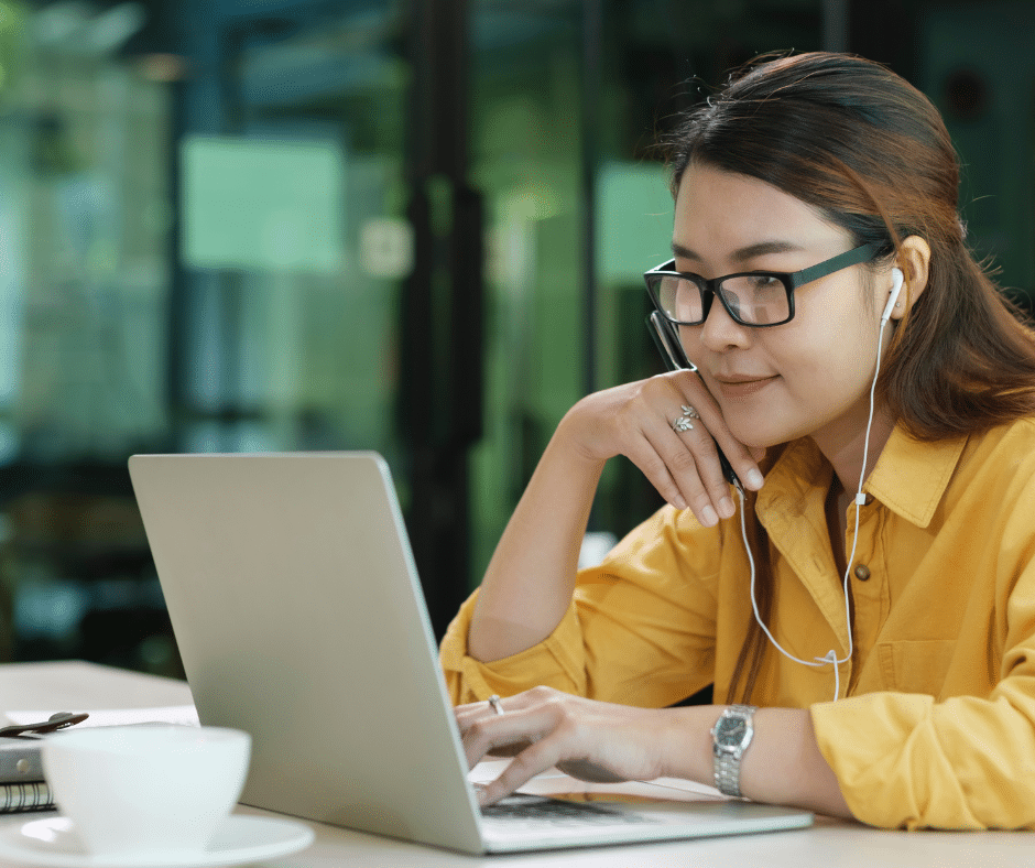 Asian woman sitting at laptop with earbuds