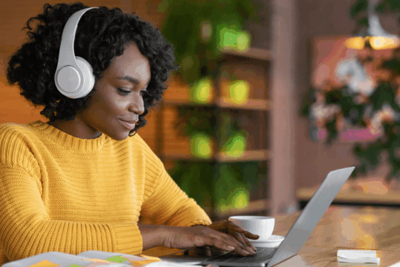 Woman wearing headphones working at laptop
